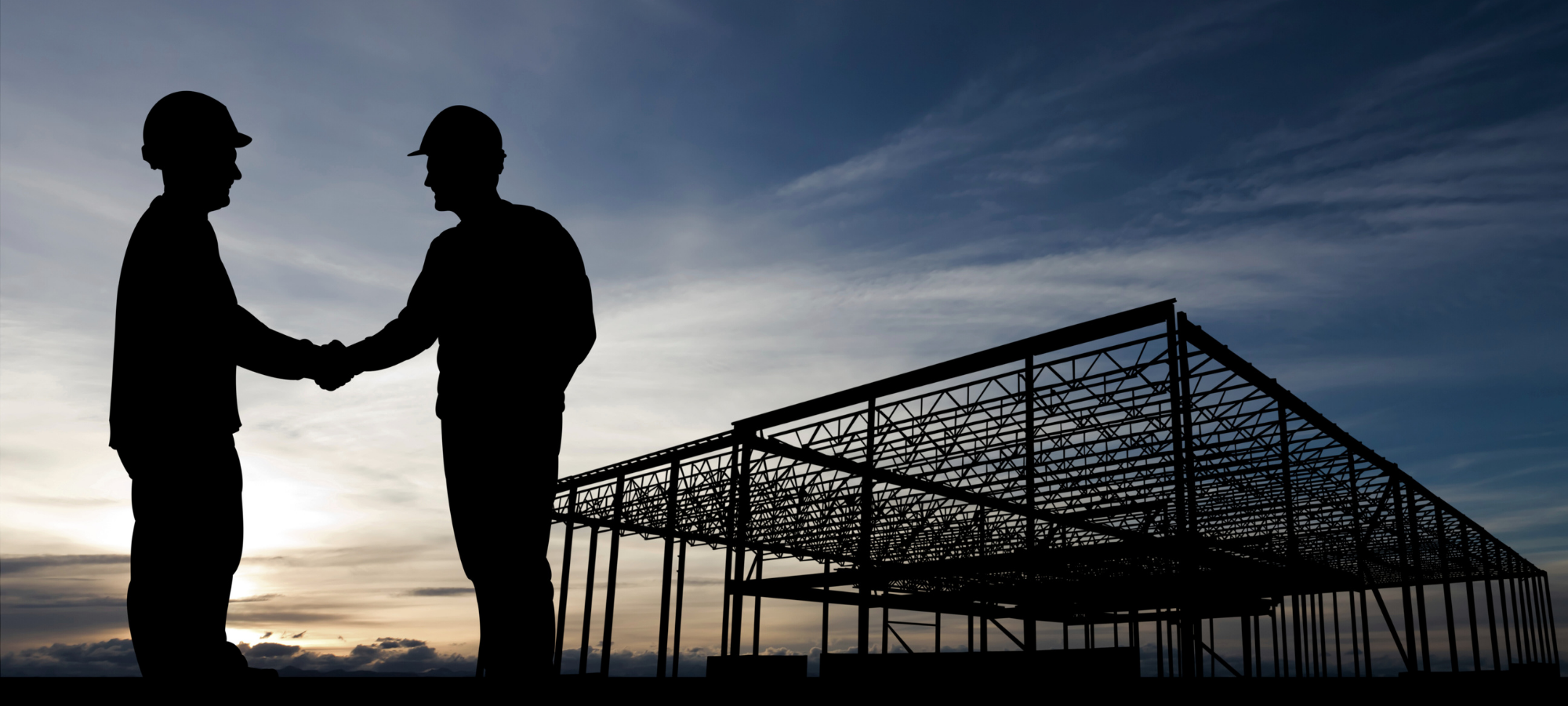 Two construction professionals shaking hands at a building site, representing Site Connected’s commitment to supporting Canadian contractors and suppliers.