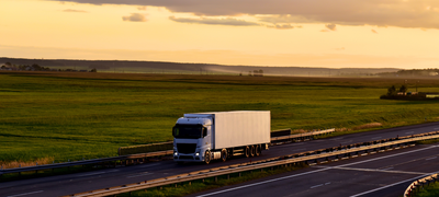 Truck driving on highway at sunset representing Site Connected’s same-day Hot Shot Delivery service for construction materials across Canada.